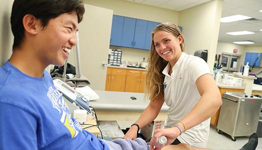 一位运动训练的学生在诊所里帮助病人康复